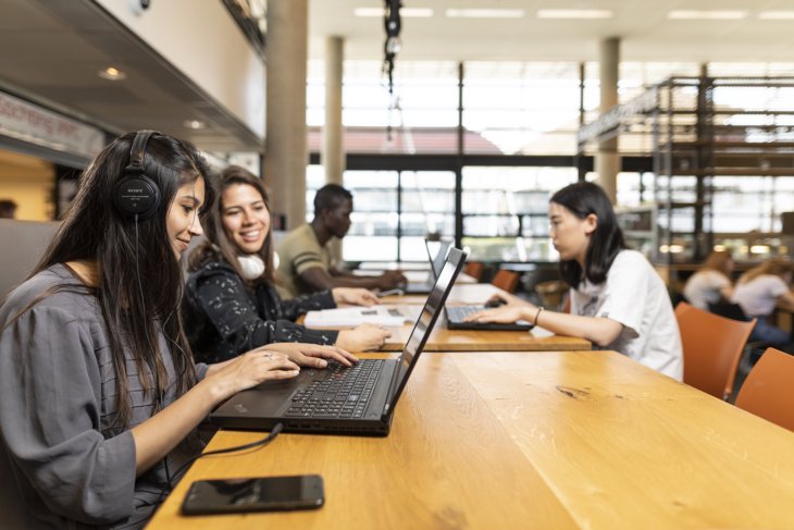 Students working on their laptops in a study area on campus.