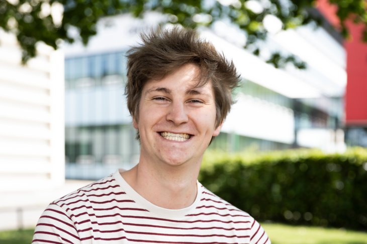 Student Mark sits outside and smiles into the camera.