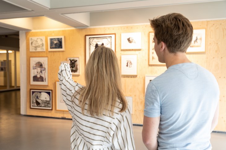 Twee studenten bezoeken een expositie.